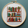 close-up-cross-stitched-picture-shelf-books-plants