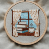 close-up-cross-stitched-picture-window-cup-coffee