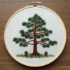 embroidery-pine-tree-pine-cones-wooden-surface